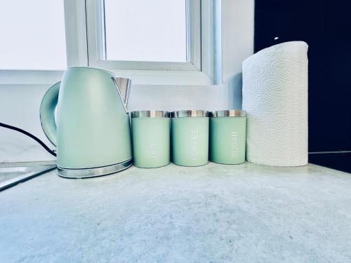 a group of cups sitting on a counter next to a window at Luxury 1B Chalet wt free parking nr LTN Airport, L&D Hosp, Whipsnade Zoo, fast trains to Central London in Luton