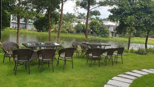 a group of tables and chairs in front of a lake at Biệt Thự chủ nhà tự doanh tại FLAMINGOS ĐẠI LẢI RESORT in Phúc Yên