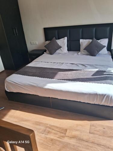 a bedroom with a large bed with a black headboard at Pacific Parlase in Leh