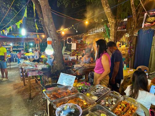 a group of people standing around a market with food at Suites by Eco Hotels in El Nido