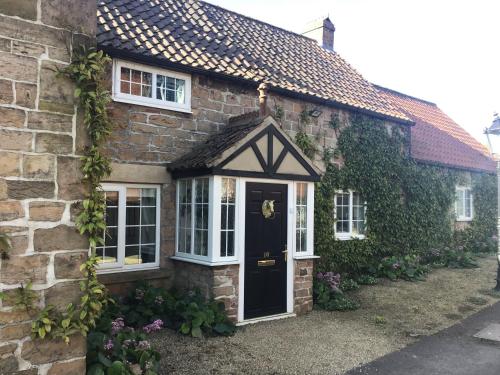 a brick house with a black door and windows at Rose Cottage in Nottingham