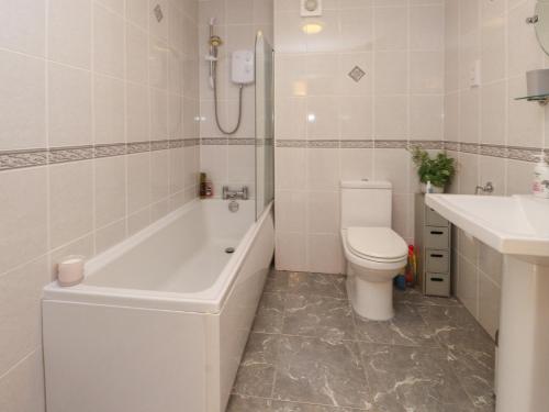 a bathroom with a tub and a toilet and a sink at 5 Stad Clynnog in Llanfairpwllgwyngyll