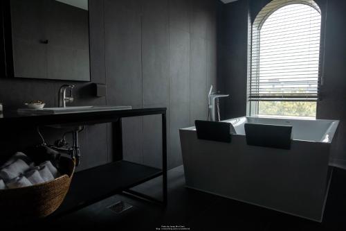 a bathroom with a tub and a sink and a window at AG405 Hotel in Busan