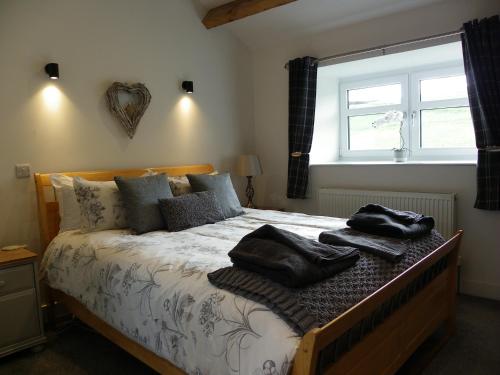 a bedroom with a bed with two black towels on it at Shay Bank Cottage in Keighley