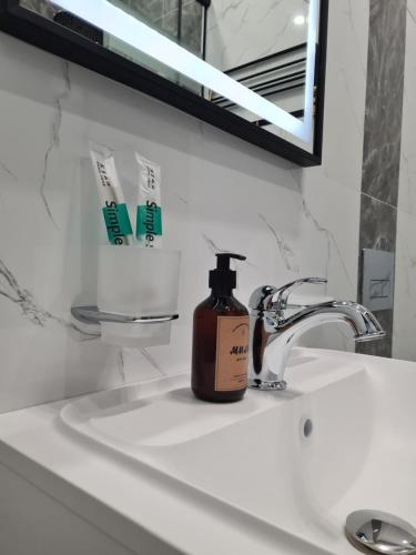 a bottle of soap sitting on a bathroom sink at Soul Park в шаге от Хан шатыр in Astana