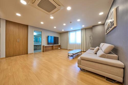 a living room with a couch and a flat screen tv at Pampas Hotel Jeju in Jeju