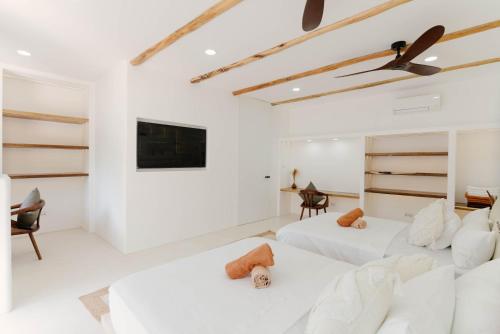 a white room with two beds and a tv at Hoshi Villas in General Luna