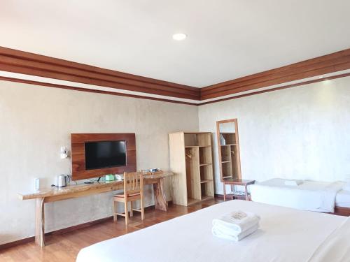 a room with a bed and a desk and a tv at Spring Hill Hotel Ruteng in Ruteng