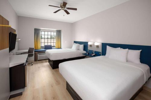 a large hotel room with two beds and a desk at Microtel Inn & Suites by Wyndham Buda Austin South in Buda