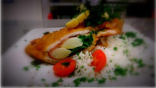 a piece of fish on a plate with rice and tomatoes at Hotel Gasthof Tirolerwirt in Bischofshofen