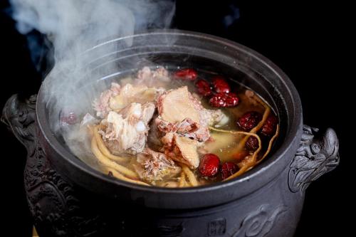 a pot of food with meat and berries in it at Honglu Garden Hotel Bell and Drum Tower Huimin Street Store & 2 bottles of beer for free in Xi'an