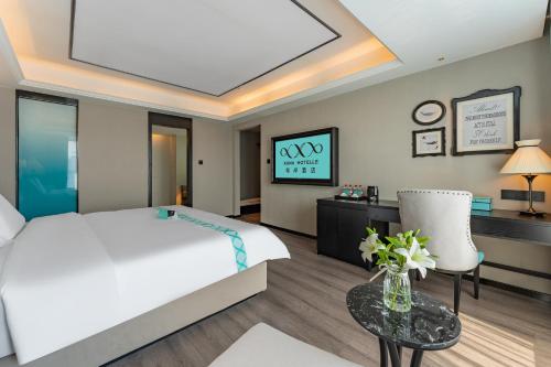 a bedroom with a bed and a table and a tv at XANA Hotel Qionghai Municipal Government High-speed Railway Station in Qionghai