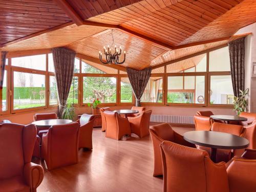 a restaurant with tables and chairs and windows at Puigcerda Park Hotel in Puigcerdà