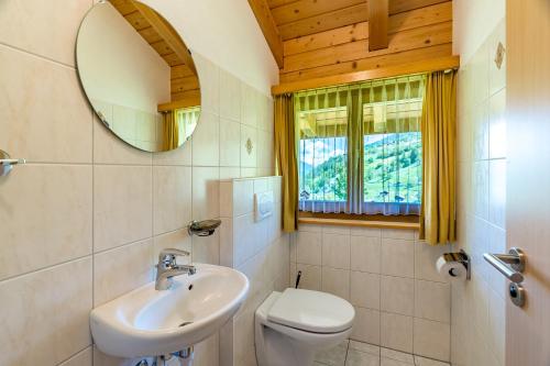 a bathroom with a sink and a toilet and a mirror at Gästehaus auf Camping Grächbiel in Grächen