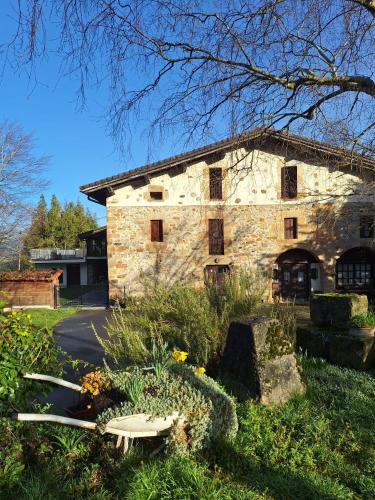 an old stone building with a bench in a garden at Casa Rural Areano in Escoriaza