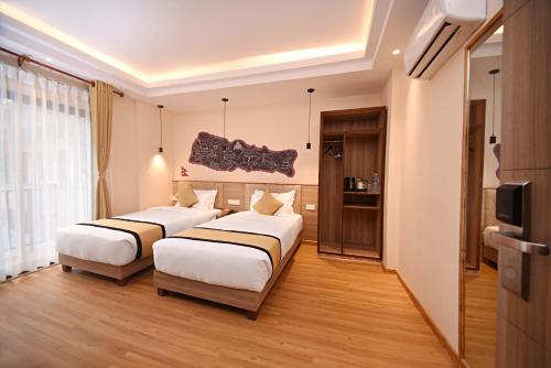 a hotel room with two beds and a television at Temple Suites Kathmandu in Kathmandu