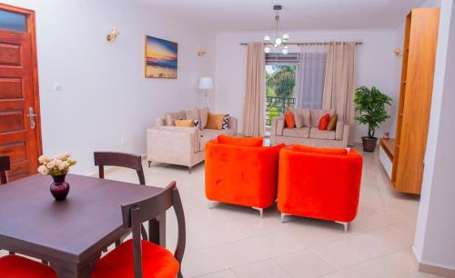 sala de estar con mesa y sillas de color naranja en Spacious & Quiet 2BR Apt with Wi-Fi Buwate Mall, en Buwate
