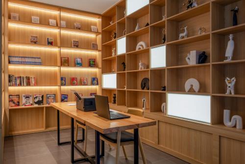 a library with wooden shelves and a desk with a laptop at 西双版纳景洪恩季国际酒店 in Jinghong
