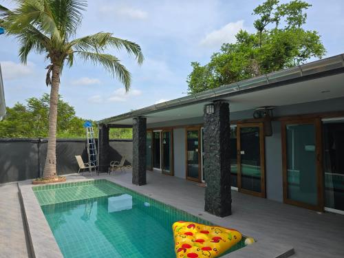 a swimming pool next to a house with a palm tree at ForestPoolvilla in Na Jomtien