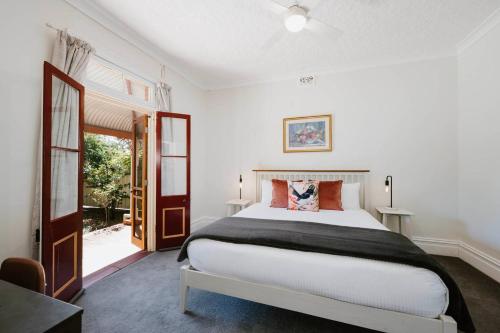 una camera da letto con un grande letto bianco e una finestra di Carinya - Federation Cottage in Central Mudgee a Mudgee