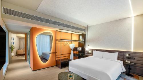 a bedroom with a large white bed and a mirror at Novotel Pune Viman Nagar Road in Pune