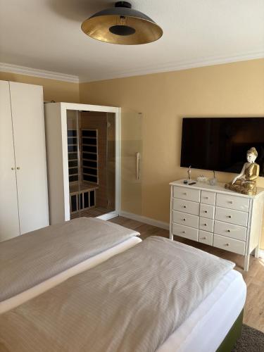 a bedroom with a bed and a dresser with a flat screen tv at das CHISTO - Ferienwohnungen im Herzen der Kneippstadt in Bad Wörishofen