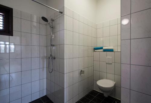 a white tiled bathroom with a toilet and a shower at Kas Rolo in Kralendijk