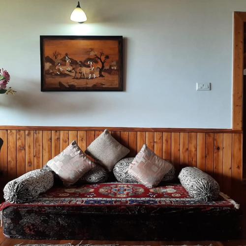 a couch with pillows and a painting on the wall at Manali House in Manāli
