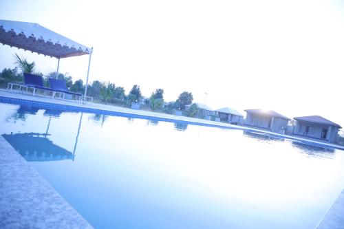 a large swimming pool with blue water and houses at Jawai Bera Leopard Camp in Bera