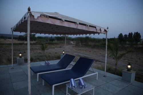 two blue chairs under an umbrella on a patio at Jawai Bera Leopard Camp in Bera