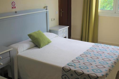 a bedroom with a bed with a green pillow on it at Hotel Playa Sol in El Arenal