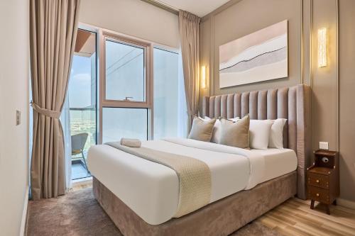 Modern High-Floor 1BR Apartment with Balcony, Pool Access & Golf Course View, Up to 4 Guests, by Stayfinity في دبي: غرفة نوم بسرير كبير مع نافذة كبيرة