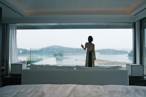 a man standing in front of a large window in a bedroom at FU VALLEY Hotel in Liyang