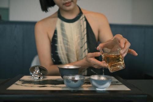 a woman is holding a drink on a tray at FU VALLEY Hotel in Liyang
