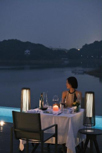 a woman sitting at a table in front of the water at FU VALLEY Hotel in Liyang