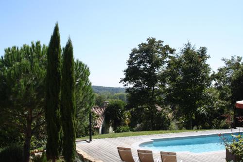 a pool in a garden with chairs and trees at La Verte Dordogne in Villars