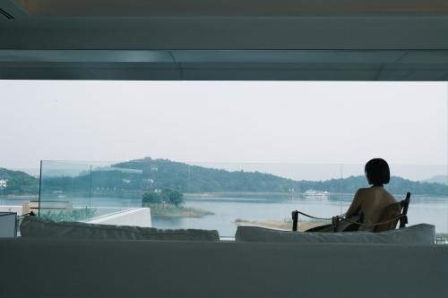 a person sitting in a chair looking out at the water at FU VALLEY Hotel in Liyang