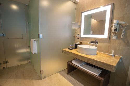 a bathroom with a sink and a mirror and a shower at Novotel Pune Viman Nagar Road in Pune