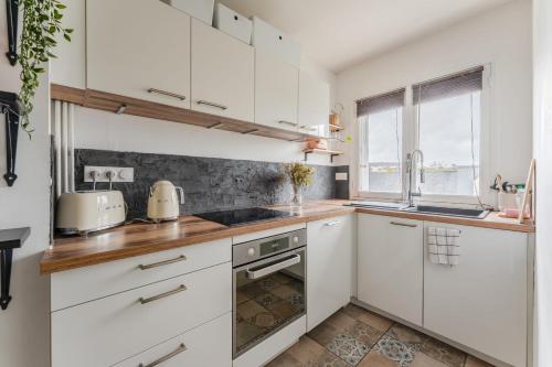 une cuisine avec des armoires blanches et une fenêtre dans l'établissement Le Nantais - Wifi - Parking, à Nantes