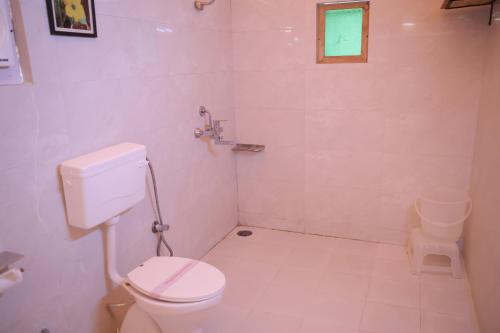 a white bathroom with a toilet and a window at Jawai Bera Leopard Camp in Bera