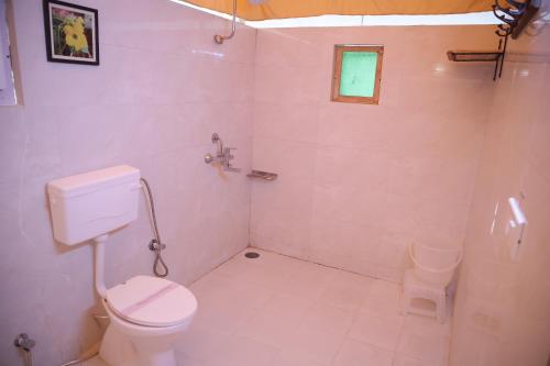 a white bathroom with a toilet and a shower at Jawai Bera Leopard Camp in Bera