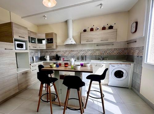 - une cuisine avec une table et des tabourets dans l'établissement Chez Axelle - Maison T4 - Vue panoramique sur Moissac, à Moissac