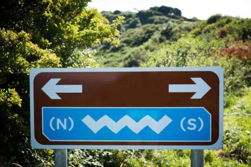 a brown and blue sign with arrows on a road at Eagles Nest Oceanview Hideaway in Drumaville