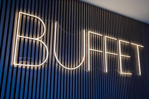 a neon sign that says bite on a wall at BeeVillage Messehotel Hannover Laatzen in Hannover
