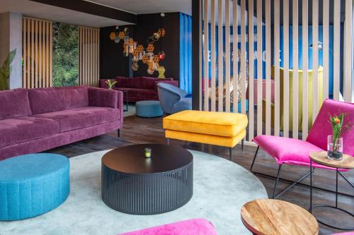 a living room with purple couches and colorful chairs at BeeVillage Messehotel Hannover Laatzen in Hannover