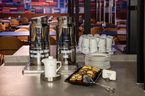 a table with two silver trophies and a plate of food at BeeVillage Messehotel Hannover Laatzen in Hannover
