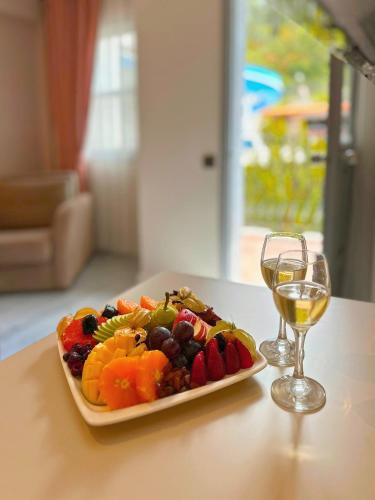 a plate of fruit on a table with a glass of wine at Casa De Levıssı Ölüdeniz in Oludeniz