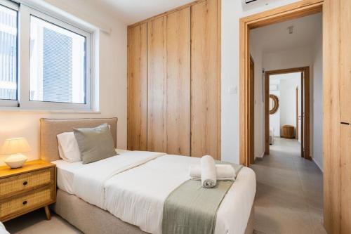 a bedroom with a large bed and a wooden wall at Aelia - Chic 2-BR Apartment & Balcony in Larnaca in Larnaca