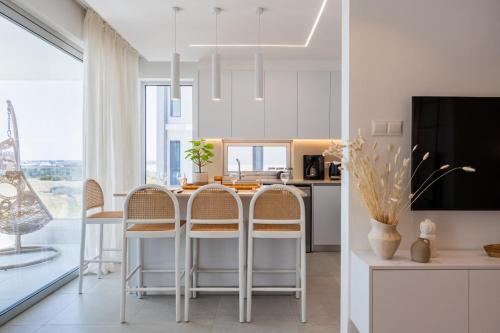 a white kitchen with a table and chairs and a tv at Aelia - Chic 2-BR Apartment & Balcony in Larnaca in Larnaca
