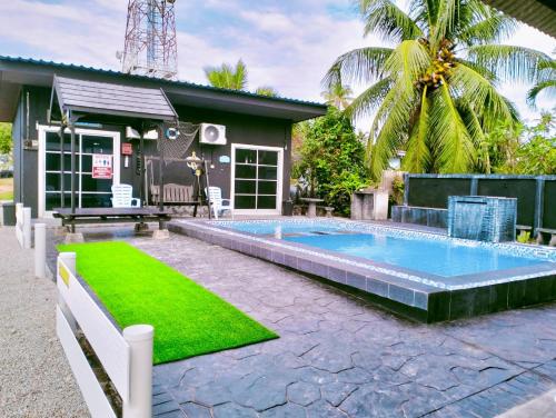 a swimming pool with green grass next to a house at Penarik baru homestay in Penarek